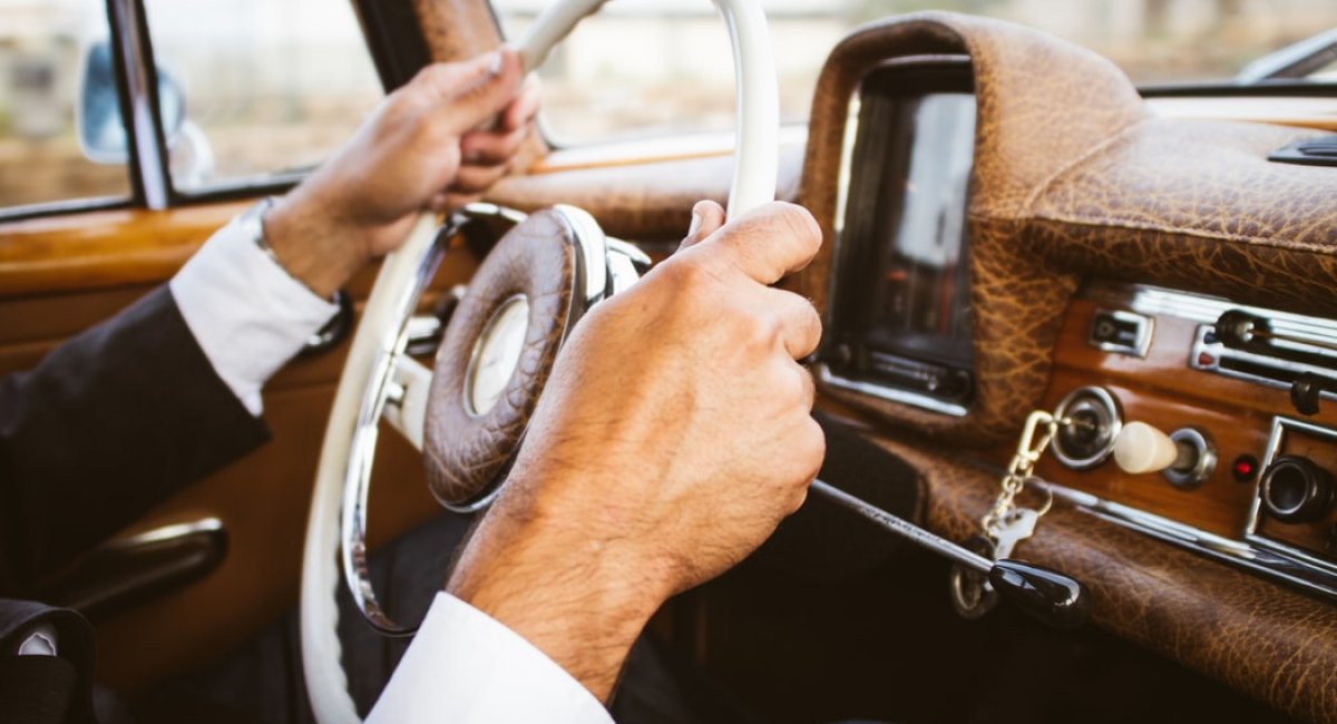 Who steers the lesson? Man's hands on the steering wheel of a car
